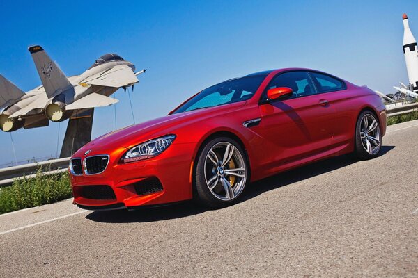 A red bmw m6 on the background of an airplane