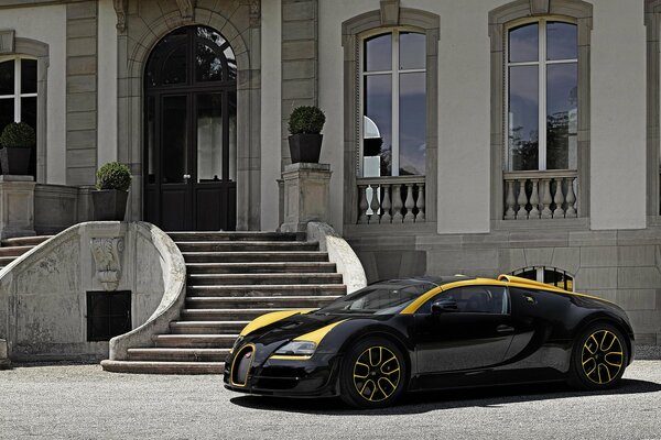 Un fantastico Bugatti nero con strisce gialle si fermò in una lussuosa villa bianca