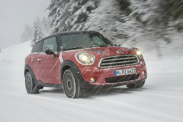 Mini Cooper en una pista cubierta de nieve en el bosque