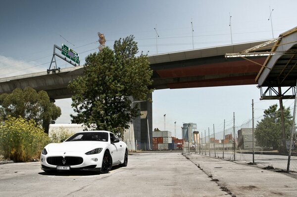 Maserati blanc sous le pont à côté de la clôture