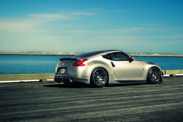 El Nissan 370Z de plata se mueve a lo largo del río