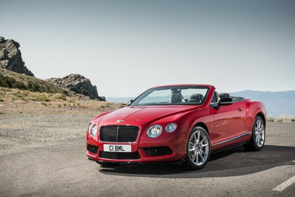 Estampa. Coche Bentley rojo 2013 en medio de las montañas