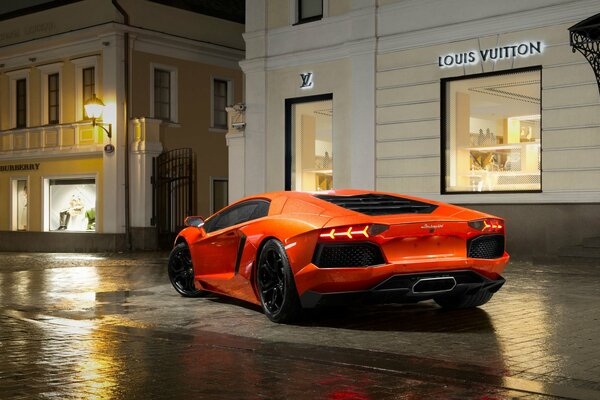 Orangefarbener Lamborghini in der Nähe einer Boutique gebremst