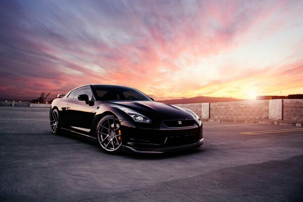 Black Nissan car on the background of a beautiful sunset