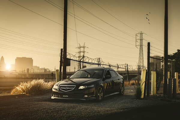 Acura negro en el sol en un distrito industrial