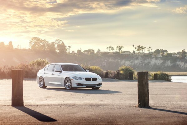 Blanco BMW sedán en el fondo de la puesta de sol