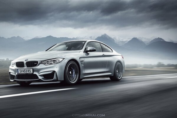 Un BMW plateado en la niebla corre por la carretera