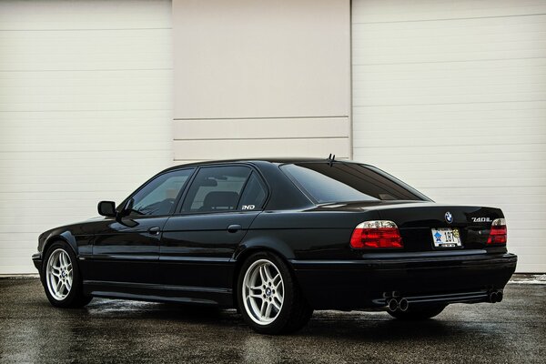 BMW E380 740iL noir vue arrière sur fond de mur beige