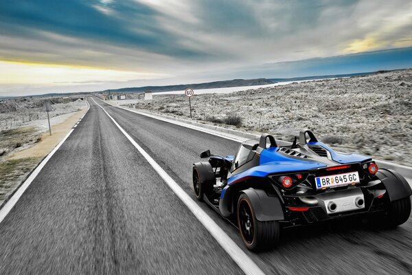 Un coche azul deportivo conduce por la carretera