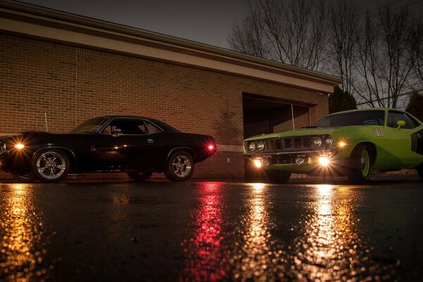 Two powerful cars of different colors, with the lights on