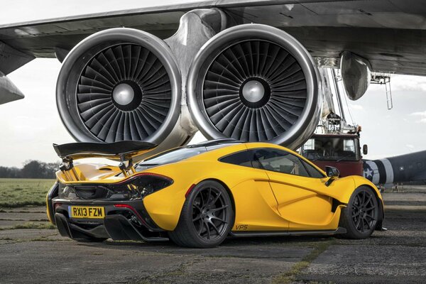 Aggressive yellow McLaren sports car on the background of aircraft engines
