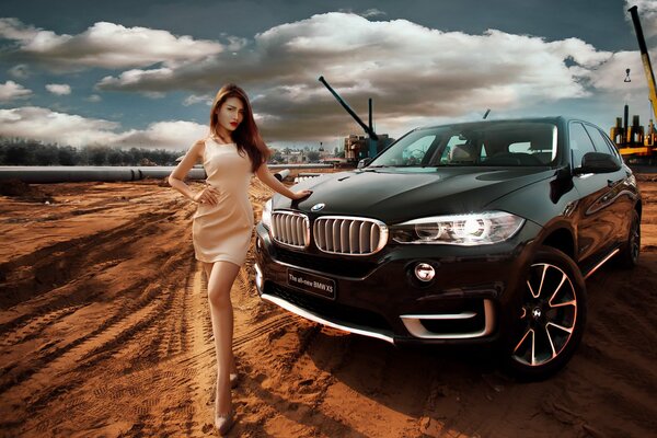 Chica al lado de BMW en el sitio de construcción