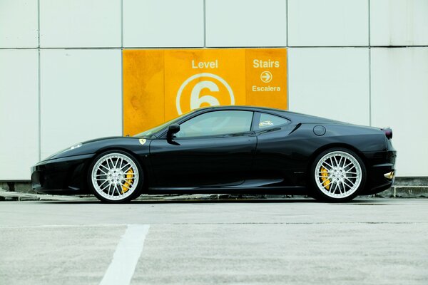 Ferari negro en la pared blanca en el estacionamiento