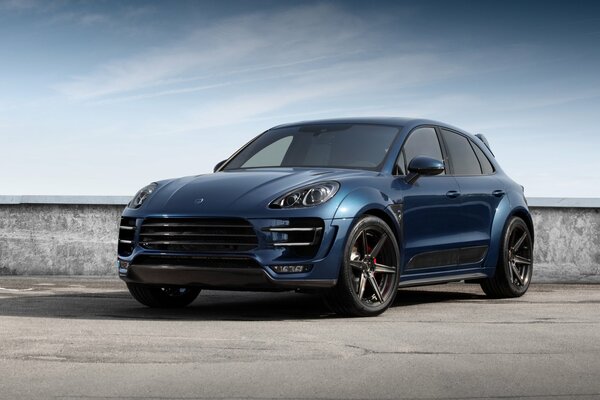 Blue car on the background of concrete fencing and blue sky