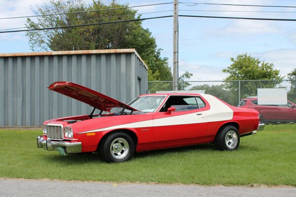 Red Ford with a white stripe on the body with an open hood