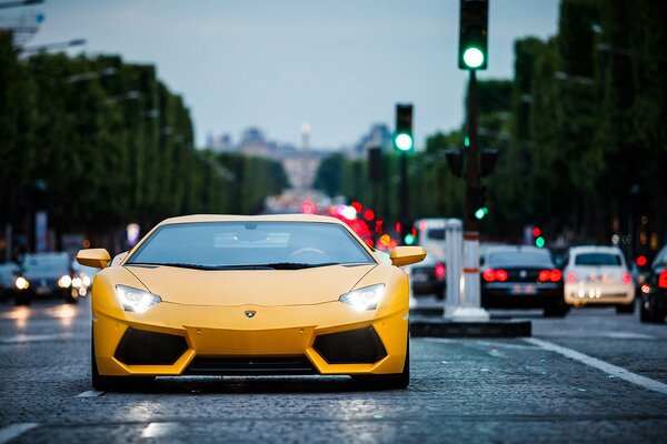 Lamborghini amarillo vista frontal, con los faros encendidos en la carretera