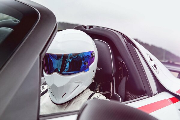 A helmeted racer in a white Porsche