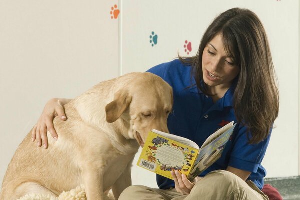 Mädchen liest ihrem Retriever ein Buch vor