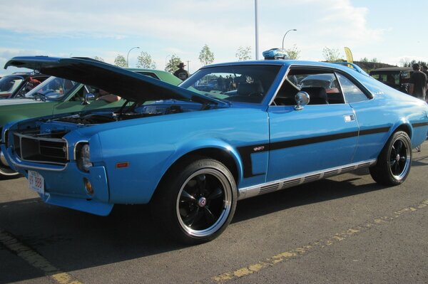 A blue car with an open hood and a black stripe on the body