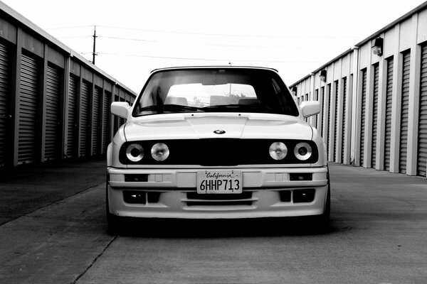 A white bmw moves along a brick wall