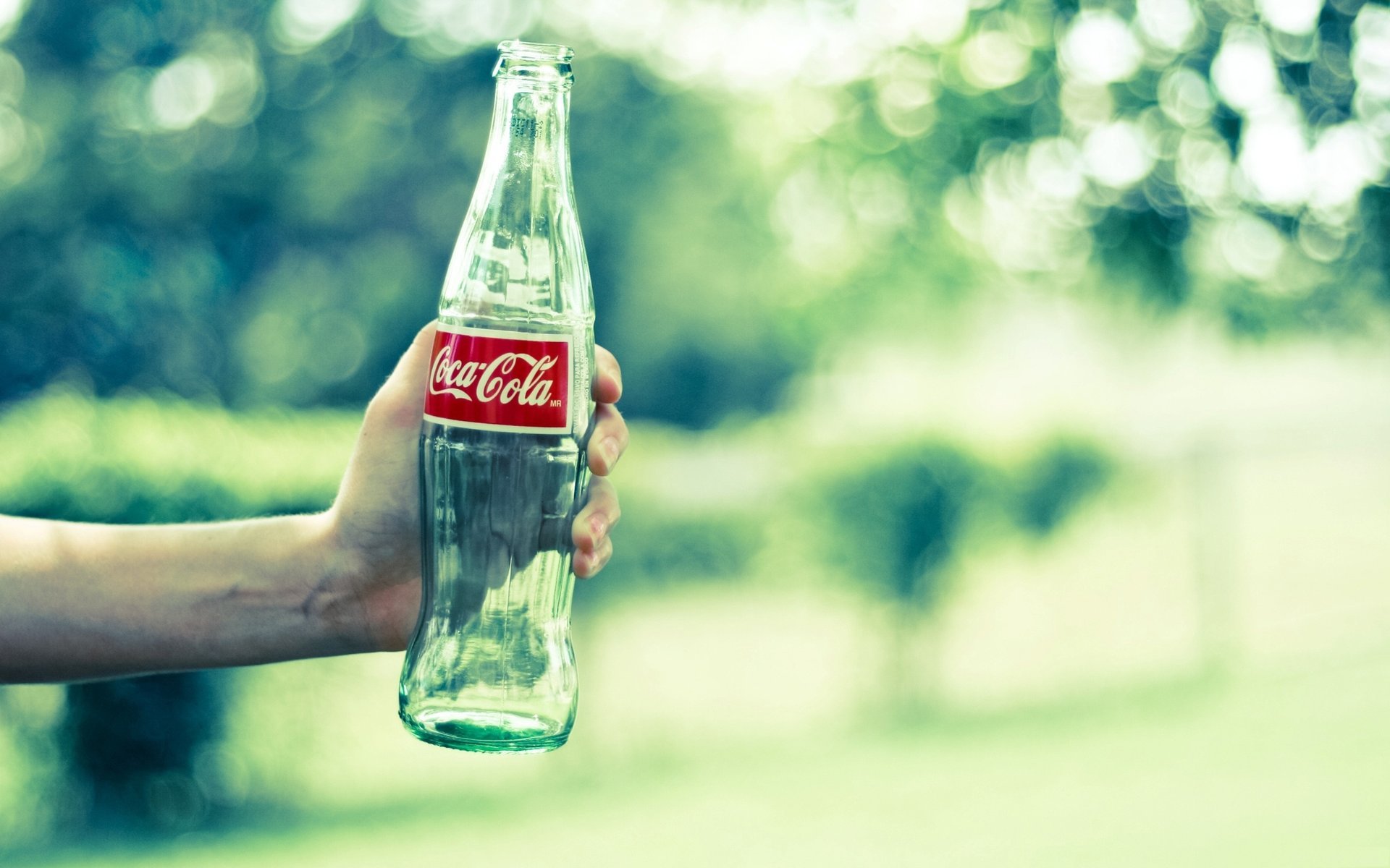 empty bottle cook kate coca-cola brand glass hand greens bottle cola drink advertising blur glare