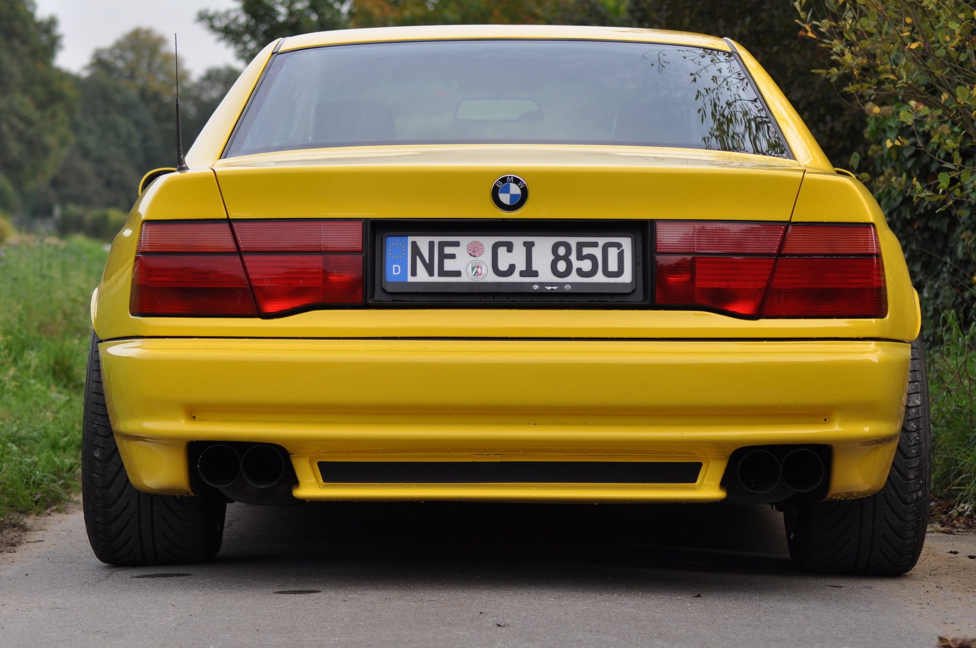 bmw 850 e31 bmw bmw coupé coche deportivo amarillo estilo diseño alta tecnología techno alemania baviera auto auto amarillo coche coche transporte hierba seto vegetación vista trasera follaje automóviles vehículos