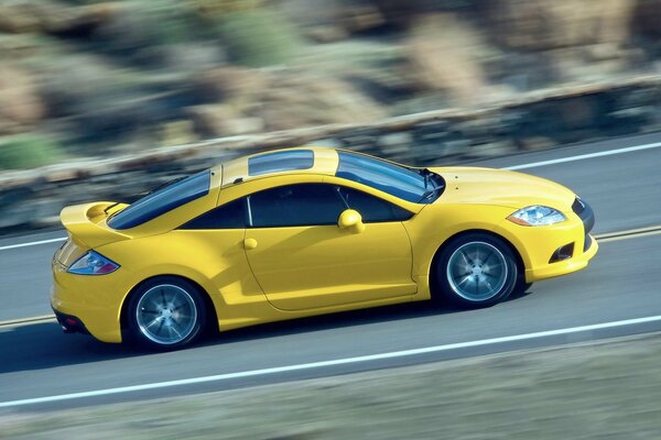 Ein helles gelbes Auto fliegt in Bewegung auf der Strecke