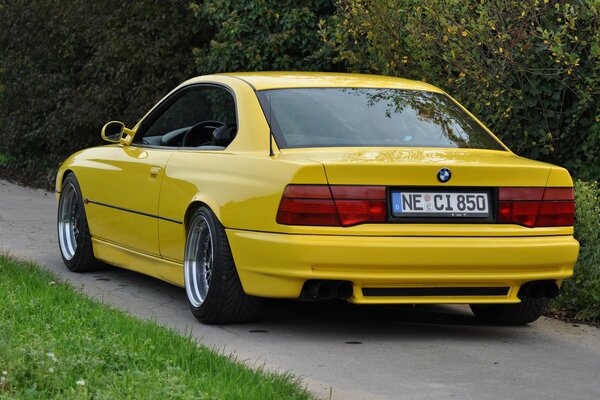 Żółty samochód sportowy BMW koło drzew