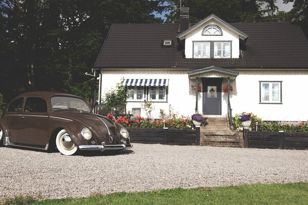 Volkwagen Beetle se encuentra en el patio de una casa de campo de una sola planta