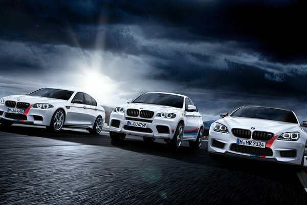 Three white BMW with red stripes in the dark