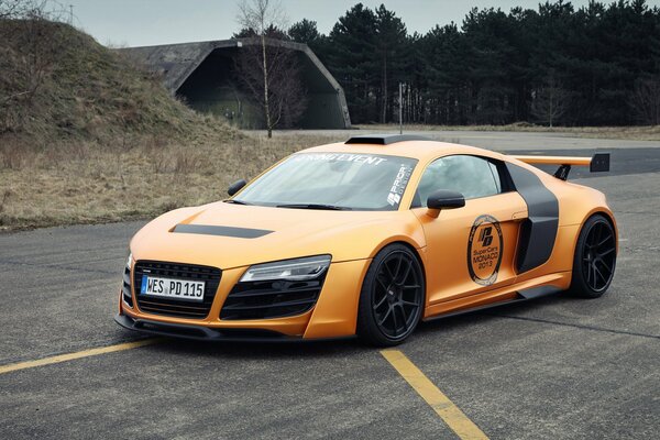 Carreras de coches de color naranja brillante de pie en la carretera