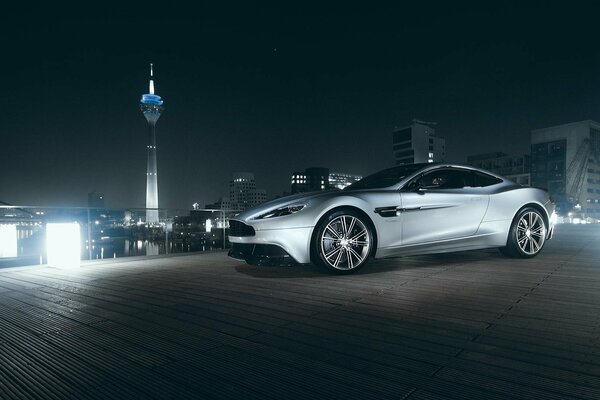 Supprkar Aston Martin nad miastem w nocy
