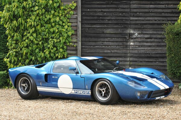 A blue racing sports car stands in profile against the background of an old building