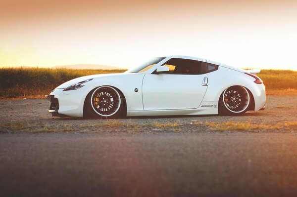 Voiture blanche de la marque nissan 370Z sur fond de coucher de soleil