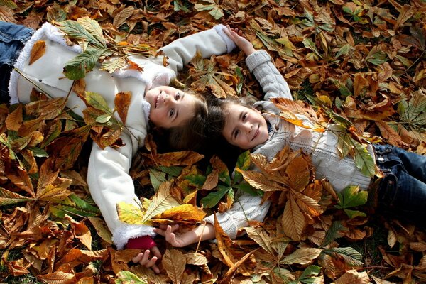 Dos chicas en hojas de otoño