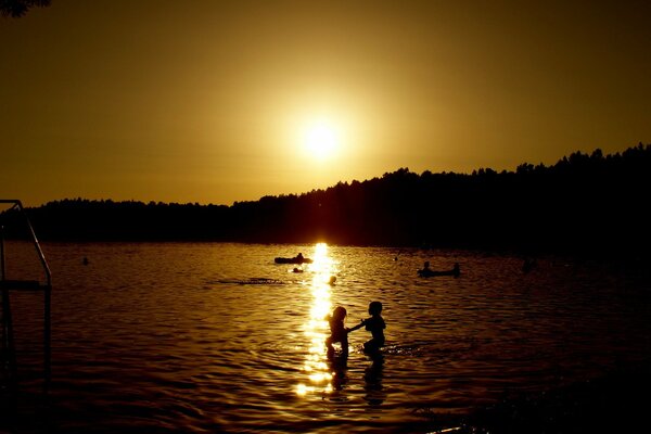 Persone che nuotano sullo sfondo del tramonto