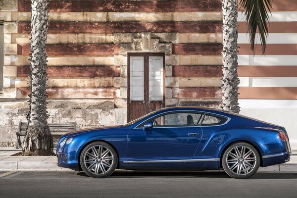 Un bentley de color azul está estacionado cerca de un edificio