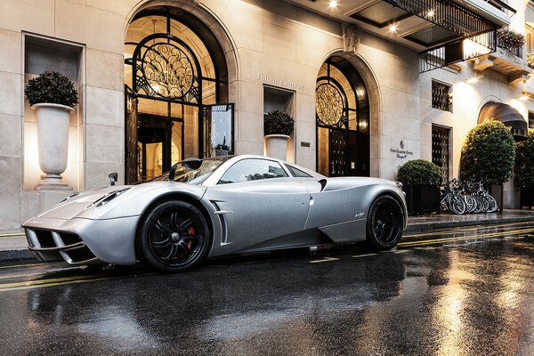 Imagen de un auto pagani huayra blanco estacionado frente al edificio