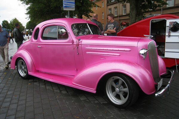 Rosa Auto vor einem großen Gebäude