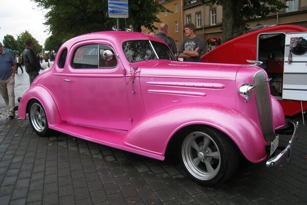Розовый автомобиль у большого здания