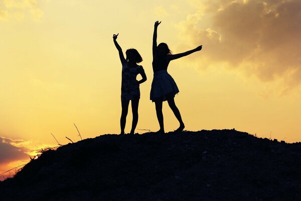 Silhouetten von zwei Mädchen bei Sonnenuntergang