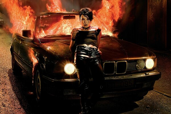 Dziewczyna na tle płonącego samochodu