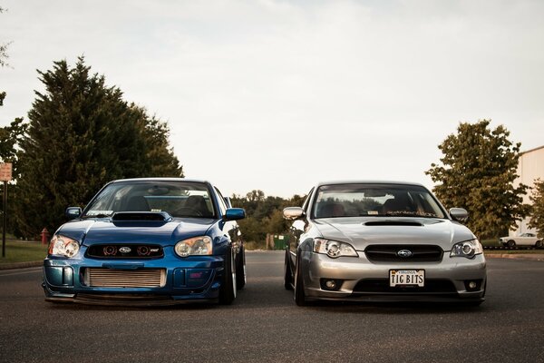 Two luxury cars - blue on the left, silver on the right