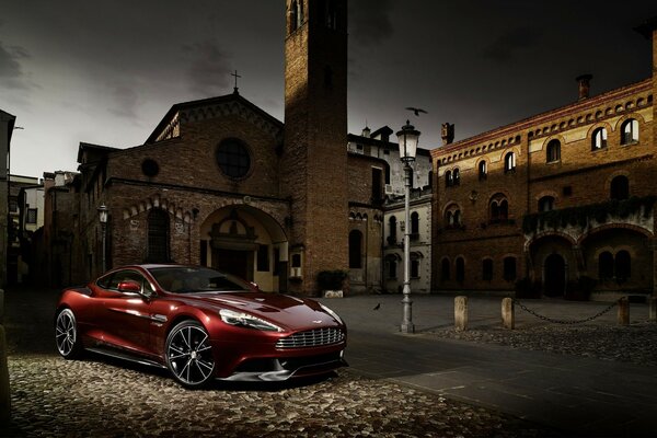 Un auto rossa aston martin m310 in un cortile semilavorato