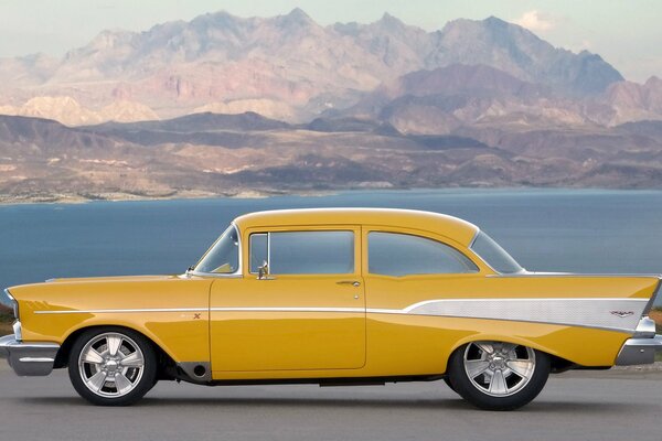 Coche retro amarillo en las montañas cerca del lago