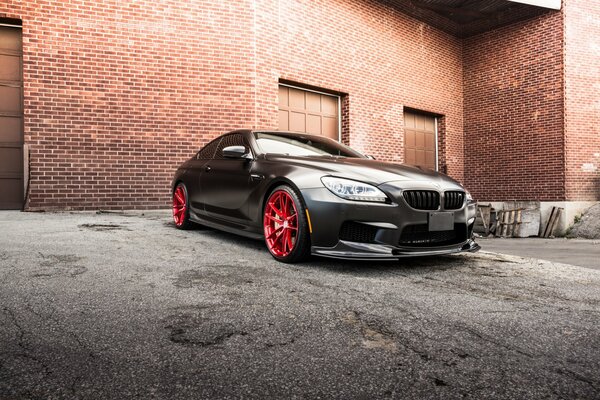 Coupé BMW noir sur fond de bâtiment de briques rouges