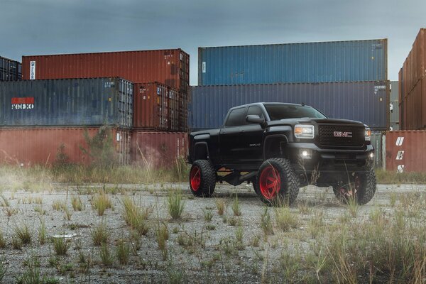 Black pickup truck with tuning on the background of containers