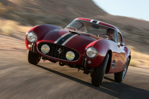 A beautiful classic Ferrari car is driving on the road