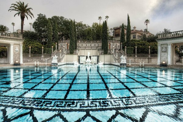 Blue pool at the resort park with stairs and cypresses