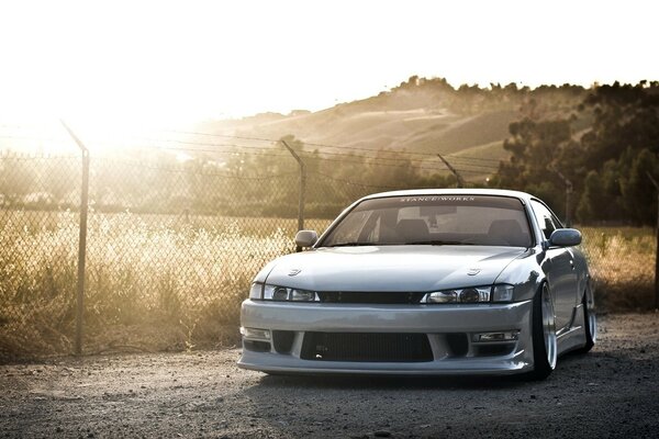 Silver Nissan at the fence against the background of mountains